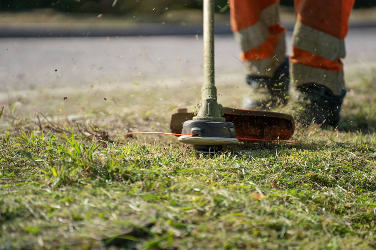 creative-approach-img Close-up of a person trimming grass with a power tool outdoors.